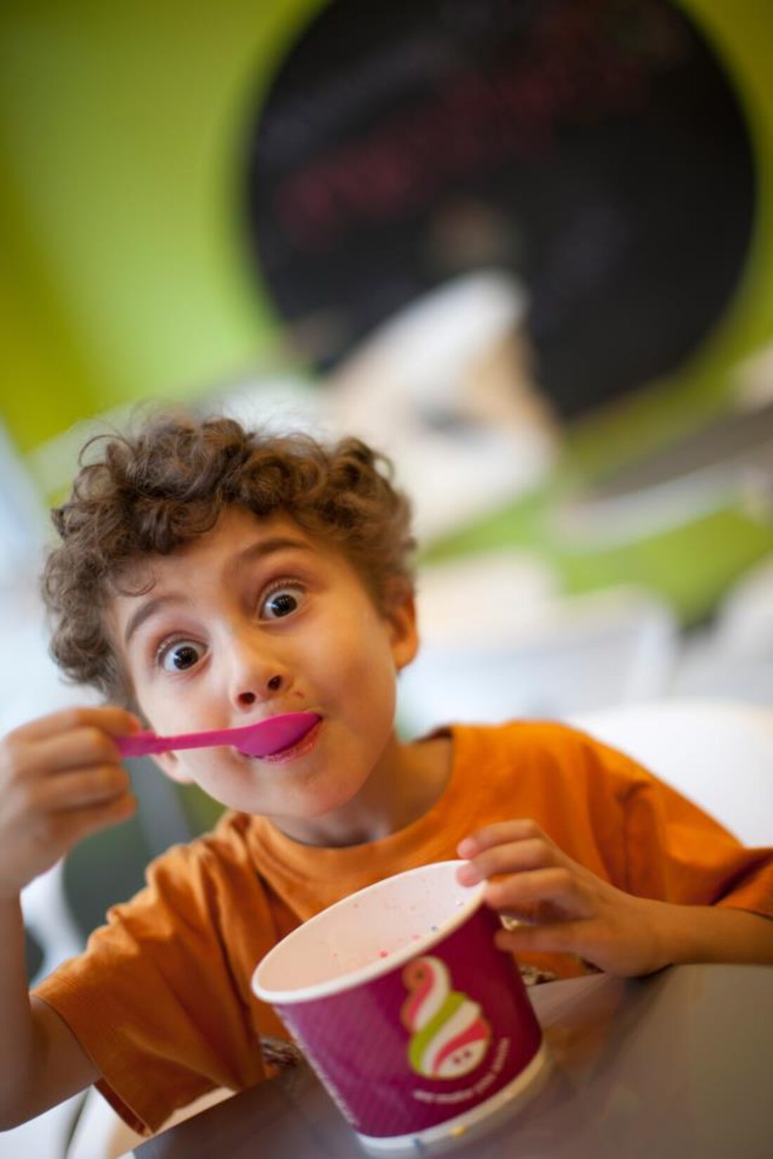 A boy enjoying a spoonful of Menchie's frozen yogurt