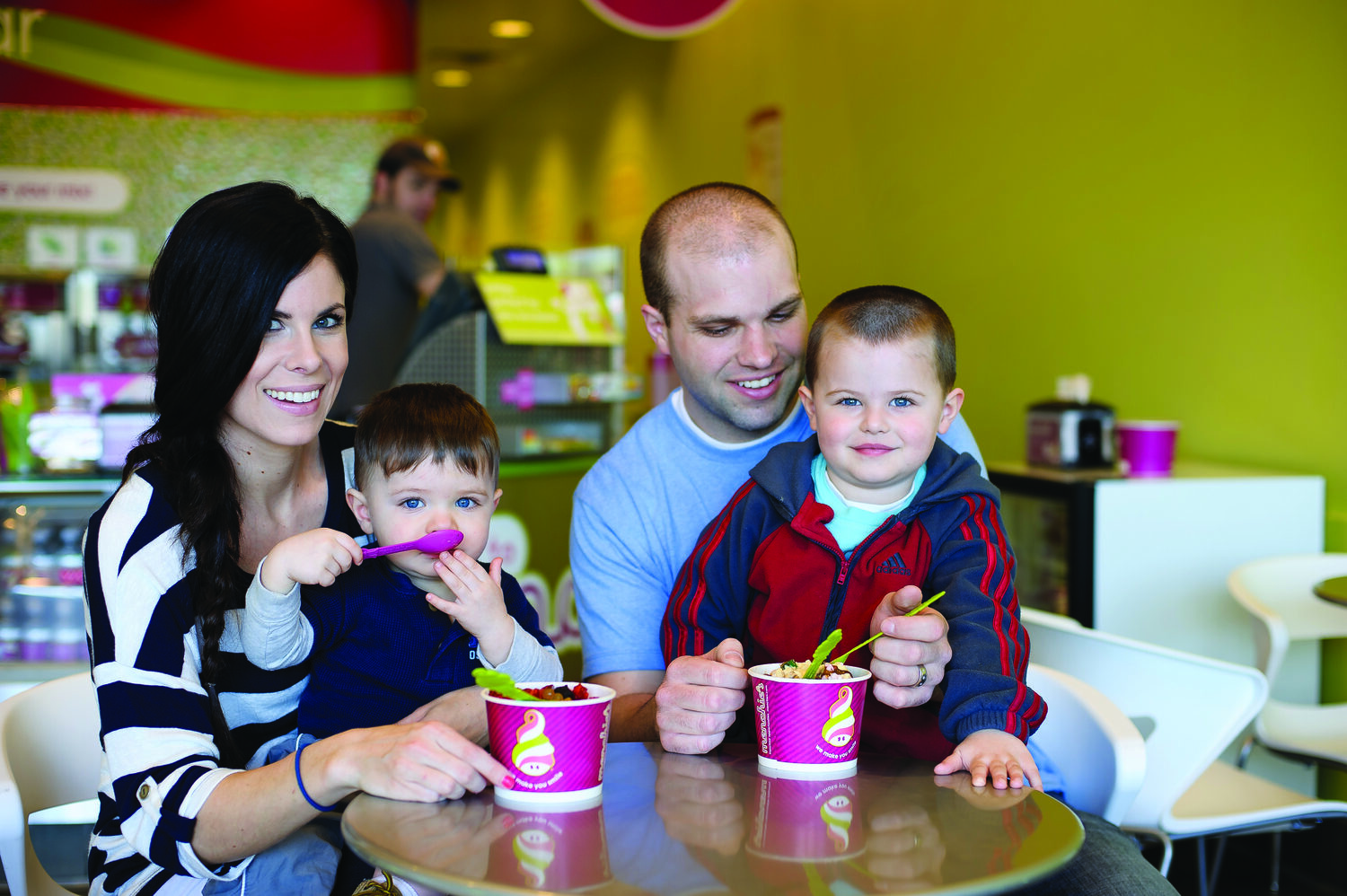 A family enjoying Menchie's frozen yogurt together inside a bright store